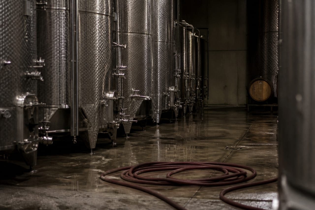 Cuves de fermentation en acier inoxydable dans un chai, vannes et robinets de prélèvement